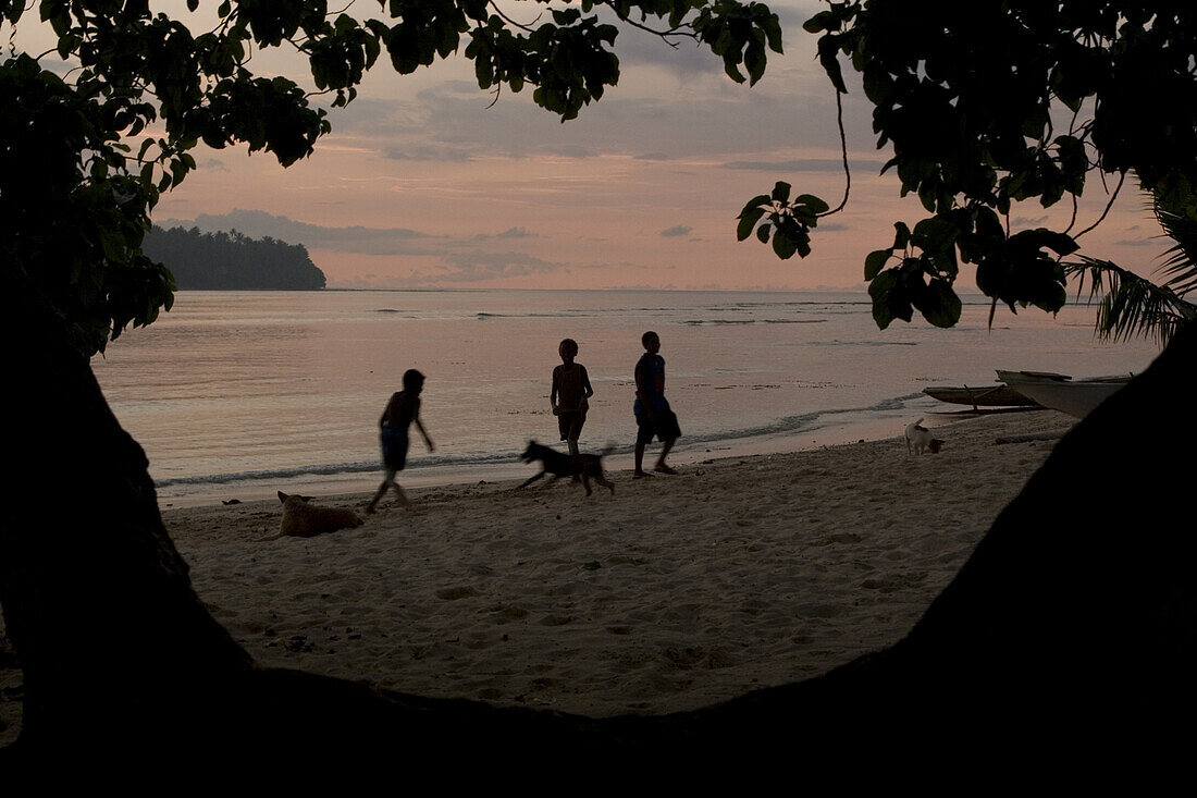 Children playing at beach in lagoon at sunset, New Ireland, Papua New Guinea