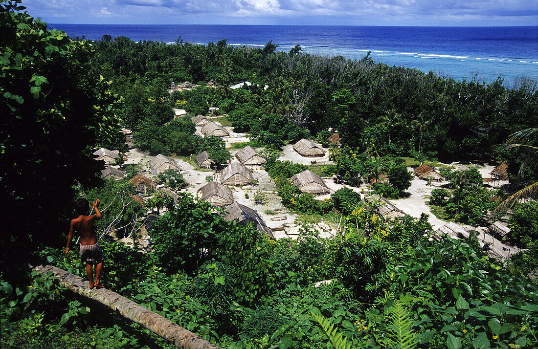 Blick auf einen Jungen und ein Dorf auf Tikopia, Salomonen, Ozeanien