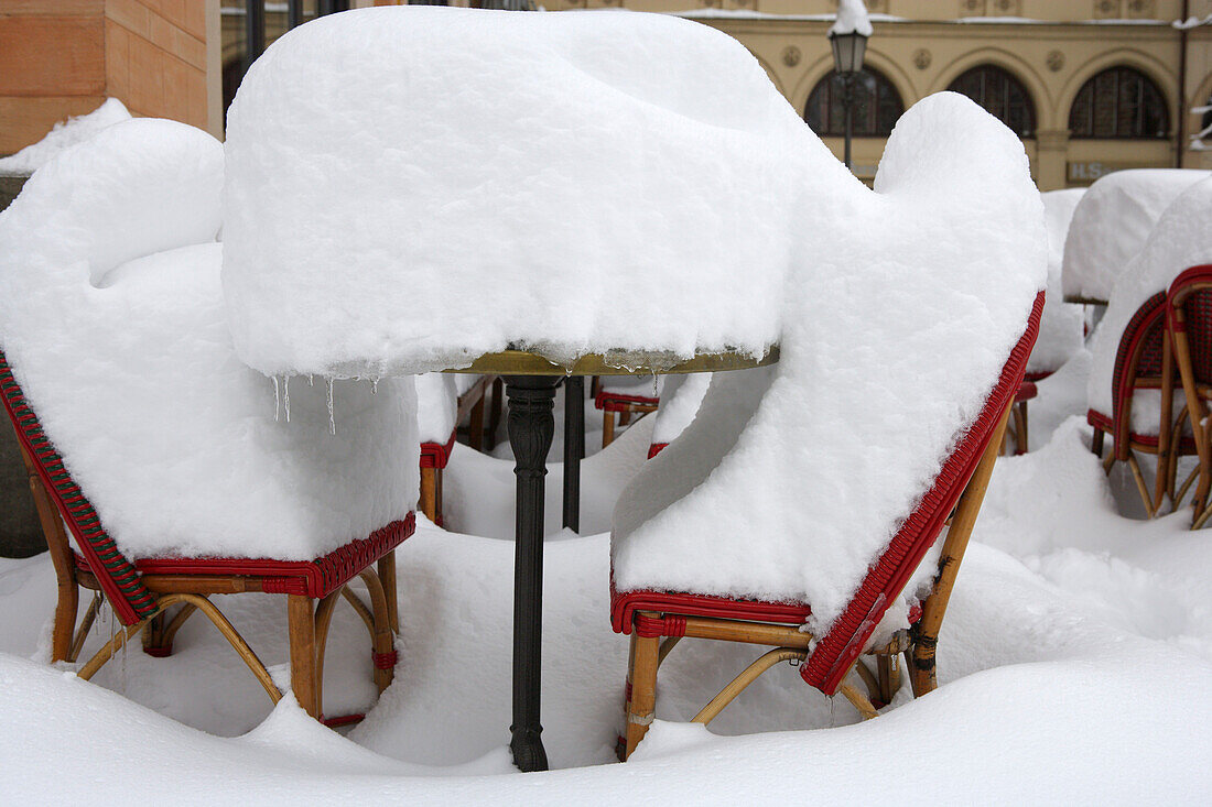 Tisch und Stühle auf der Terrasse vom Café Roma unter einer dicken Schneeschicht, Maximilianstraße, München, Bayern, Deutschland
