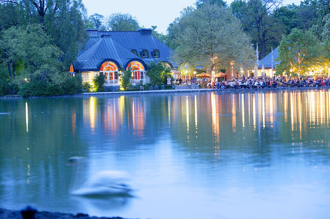 People enjoying themselves at beer garden Seehaus at lake Kleinhesseloher See, English Garden, Munich, Bavaria, Germany