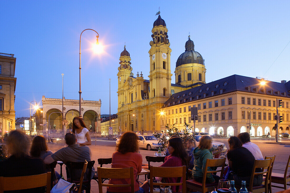 People sitting on the terrace of Cafe Tambosi, view at Feldherrnhalle and Theatinerkirche, Odeonsplatz, Munich, Bavaria, Germany