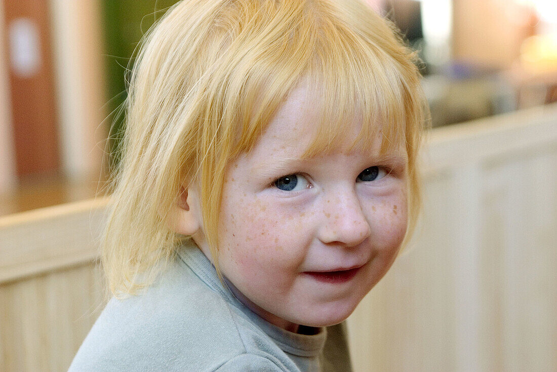 Three year old girl looking into camera, cheeky little smile