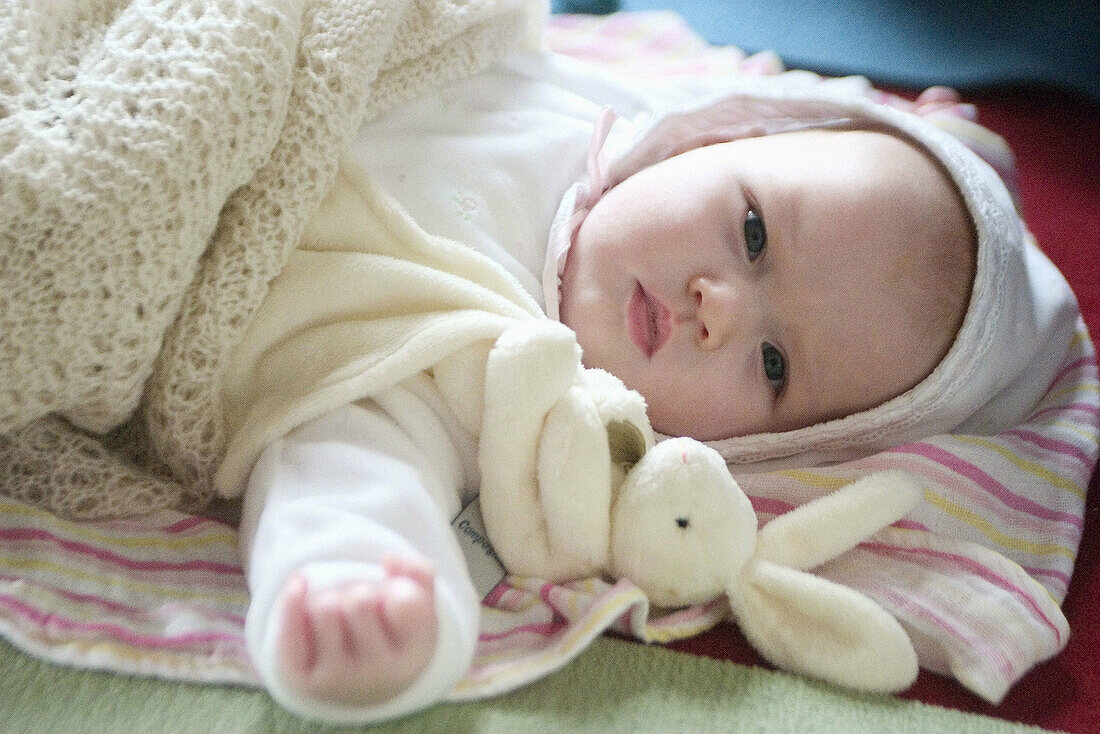 2 month old baby in bonnet, lying on back