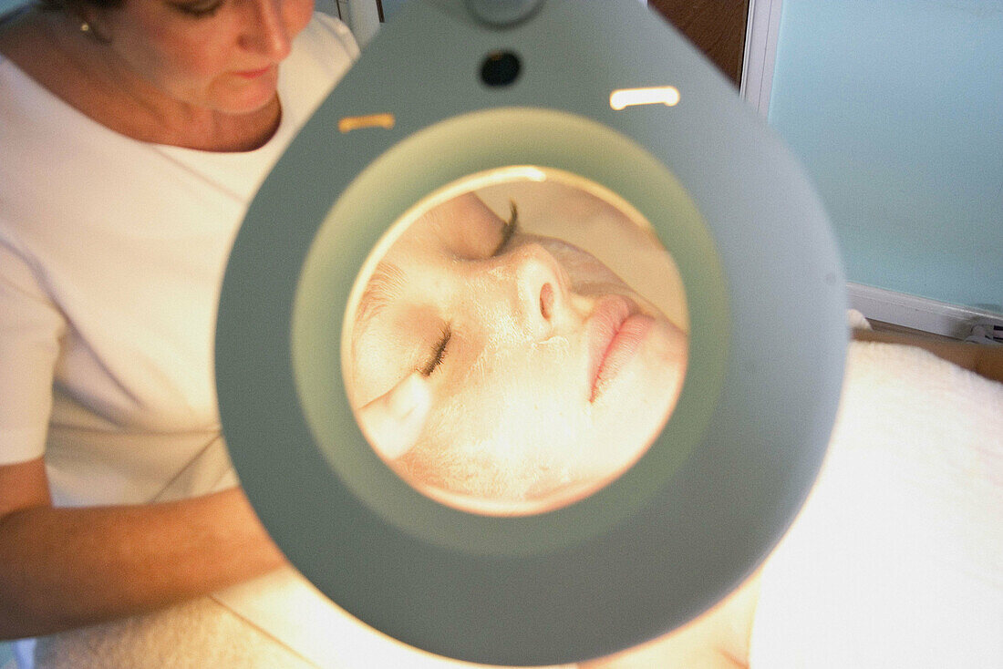 close up shot of woman having a facial through a manifying mirror, at the beauty salon