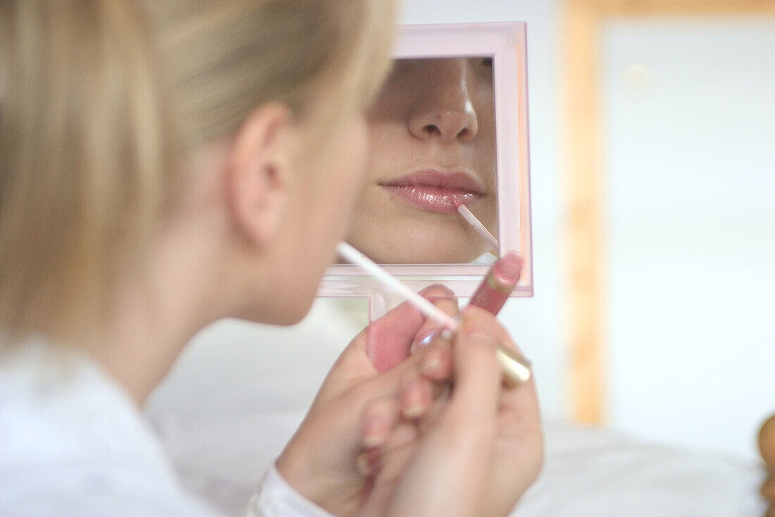 Mouth of girl putting lipstick on in a mirrror