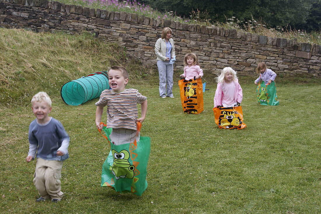 Group of pre school children doing a sack race on sports day