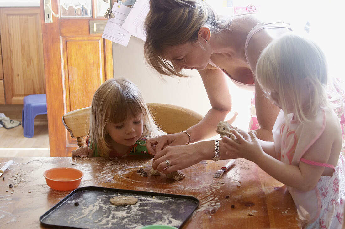 Mother baking with two three year old girls.