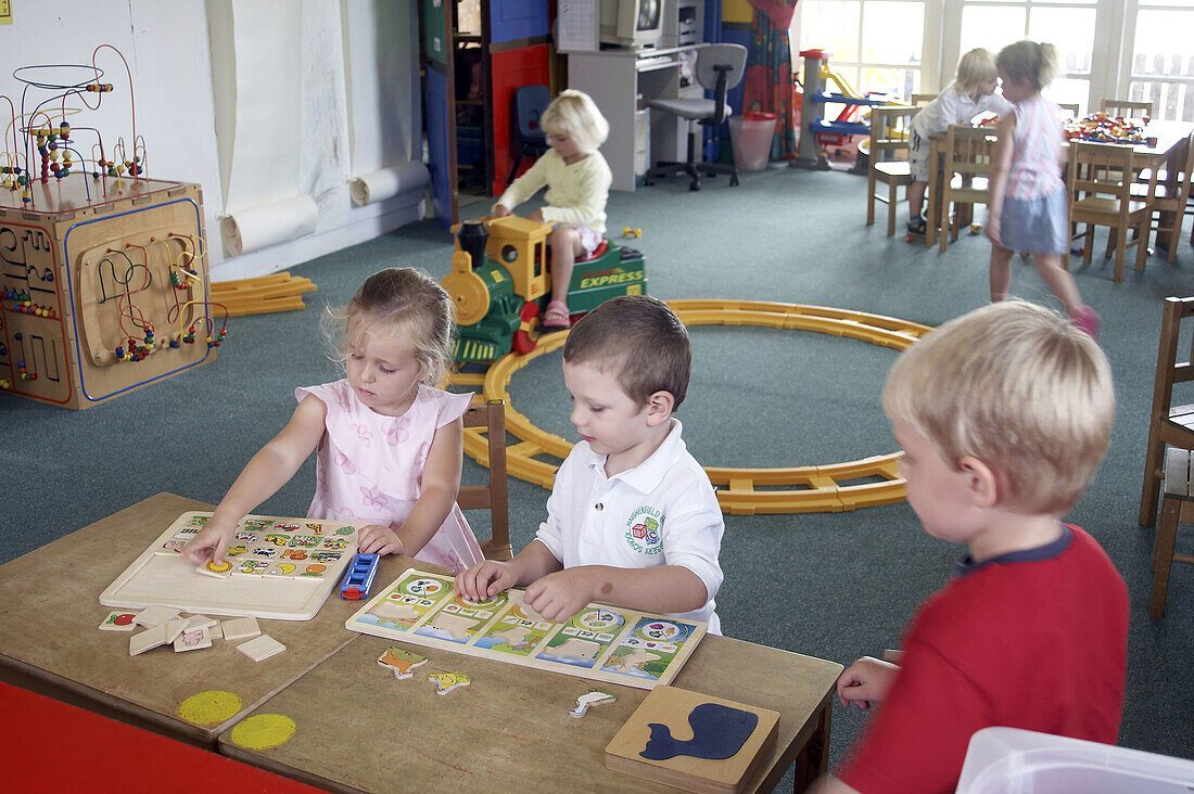 children at nursery, playing at trains and jigsaws