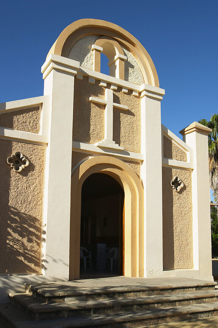 Exterior of church, arched doorway, painted stucco walls, Spanish architecture. Cabo San Lucas, Mexico