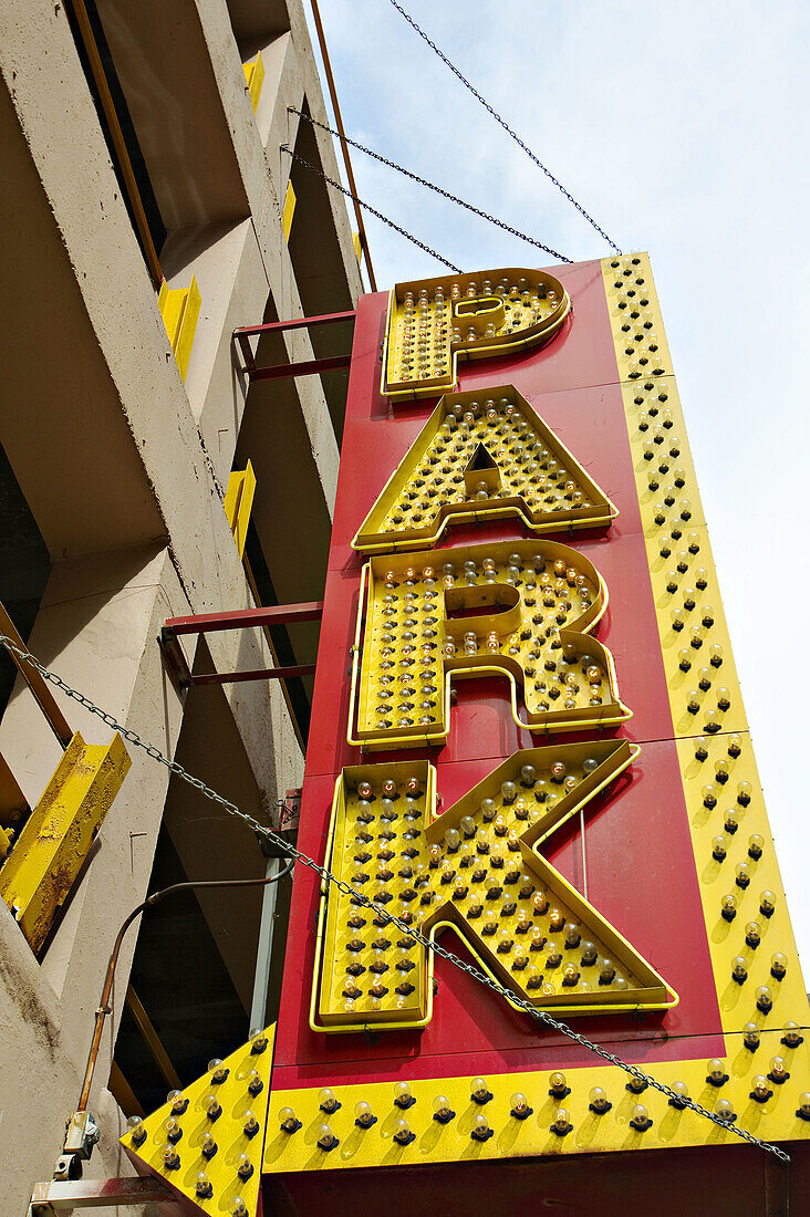 USA, Illinois, Chicago. Yellow parking sign with arrow point to garage, many lightbulbs