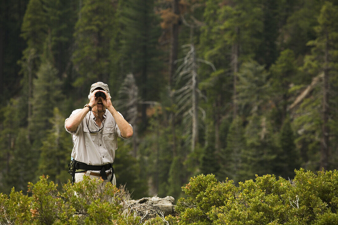 CALIFORNIA South Lake Tahoe Male day hiker use binoculars from overlook point