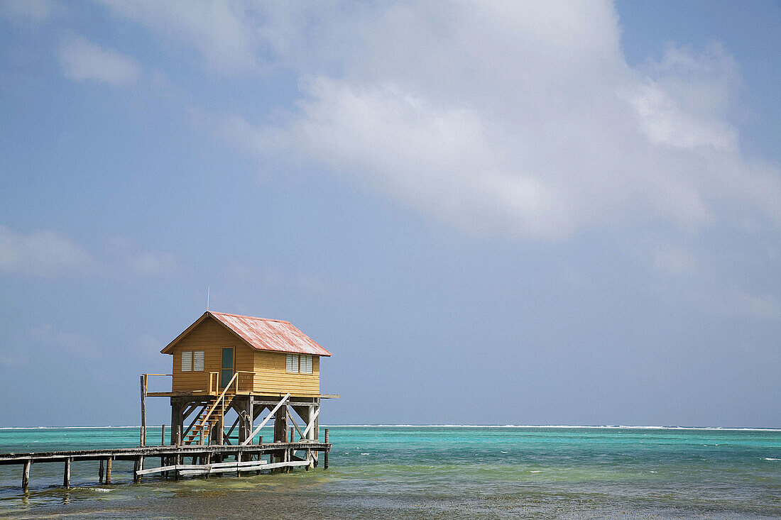 BELIZE San Pedro on Ambergris Caye Colorful wooden building on stilts, end of dock, Caribbean waters