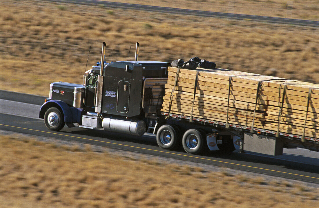 Big rig truck hauling lumber on interstate highway I-84. Northern Utah. USA.