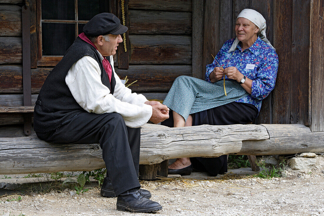 Mature couple sitting in front of a wooden house, Rocca al Mare open air museum, Tallinn, Estonia