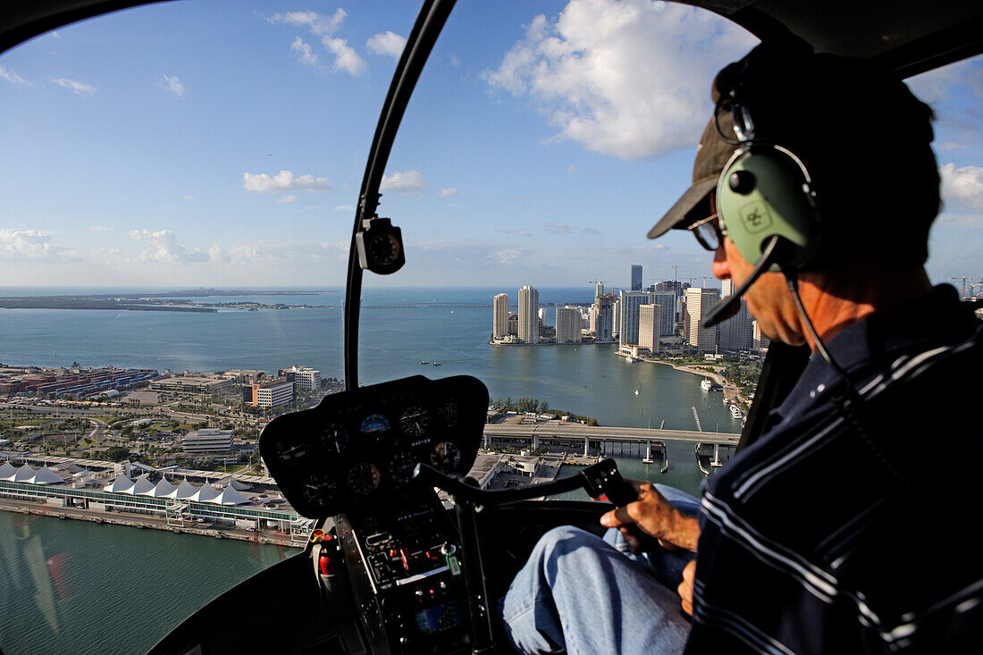 Pilot im Hubschrauber mit Blick auf Dodge Island und das Stadtzentrum von Miami, Florida, USA