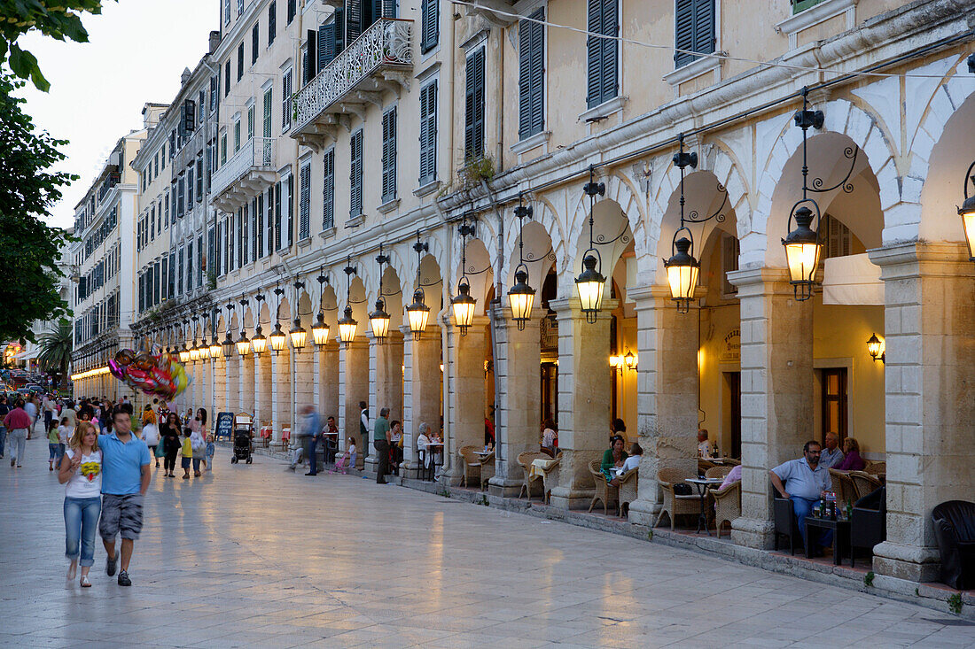 People walking through the town and sitting in cafes under the arcades of Liston, Corfu, Ionian Islands, Greece