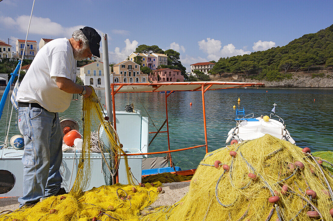 Kefalonia, ein Fischer säubert sein Netz im Hafen Assos, Ionische Inseln, Griechenland