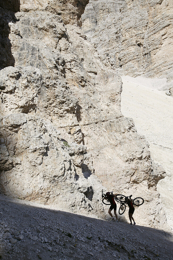 Mountain bikers carrying their bicyles, Tofane, Dolomites, Veneto, Italy