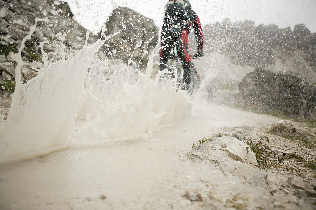 Mountainbiker fährt durch Wasserlauf, Drei Zinnen, Dolomiten, Venetien, Italien