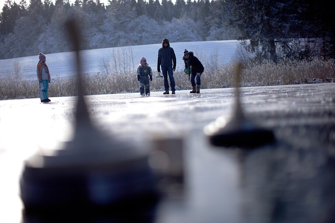Family curling on on frozen lake Buchsee, Munsing, Bavaria, Germany