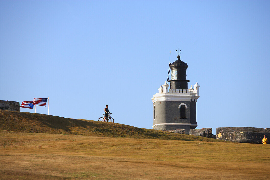 A cyclist next to the Castillo San Felipe del Morro under blue sky, San Juan, Puerto Rico, Carribean, America