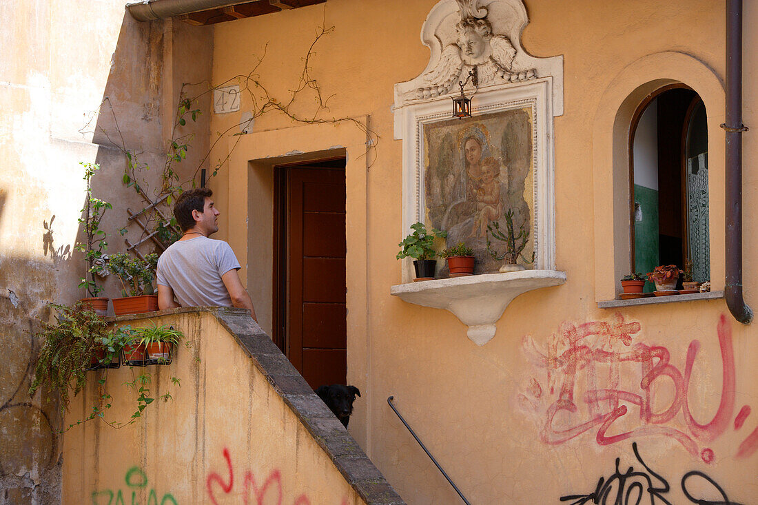 Man standing in front of the entrance of a house at the district Trastevere, Rome, Italy, Europe