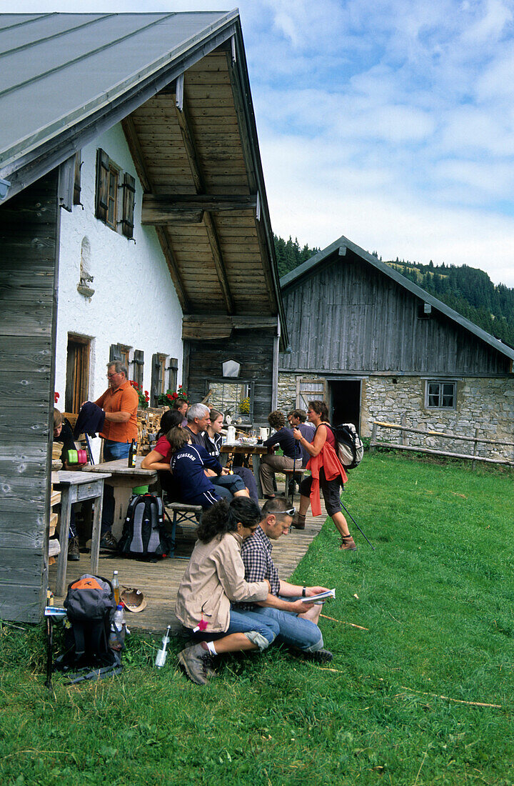 alpine hut Hofbauernalm with group of hikers on terrace, Kampenwand, Chiemgau range, Chiemgau, Bavarian foothills, Upper Bavaria, Bavaria, Germany