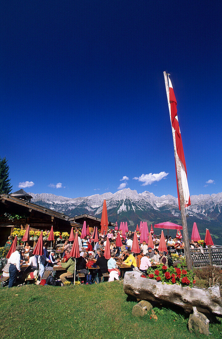 hikers on terrace of alpine hut Ruebezahlalm, view to Wilder Kaiser range, Hartkaser, Ellmau, Tyrol, Austria
