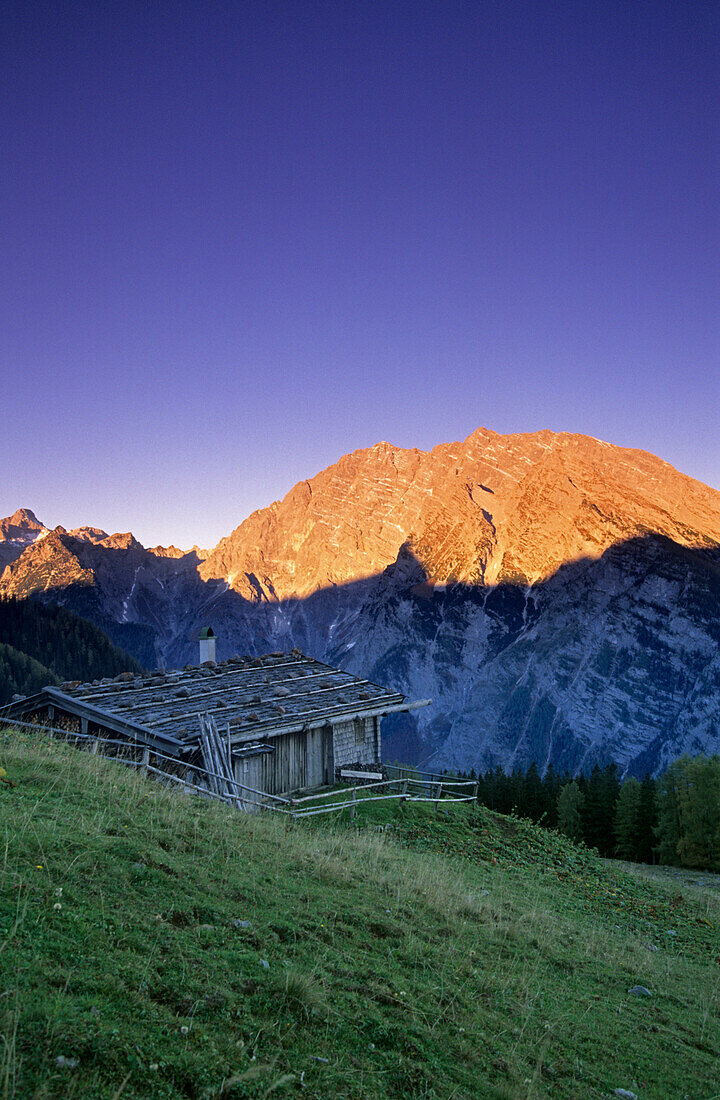 traditional alpine hut with Watzmann in alpenglow, Berchtesgaden range, Berchtesgaden, Upper Bavaria, Bavaria, Germany