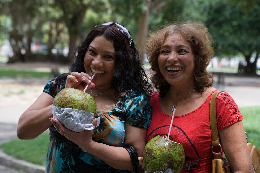 Zwei brasilianische Frauen trinken gekühltes Kokoswasser aus Kokosnüssen, Belem, Para, Brasilien, Südamerika