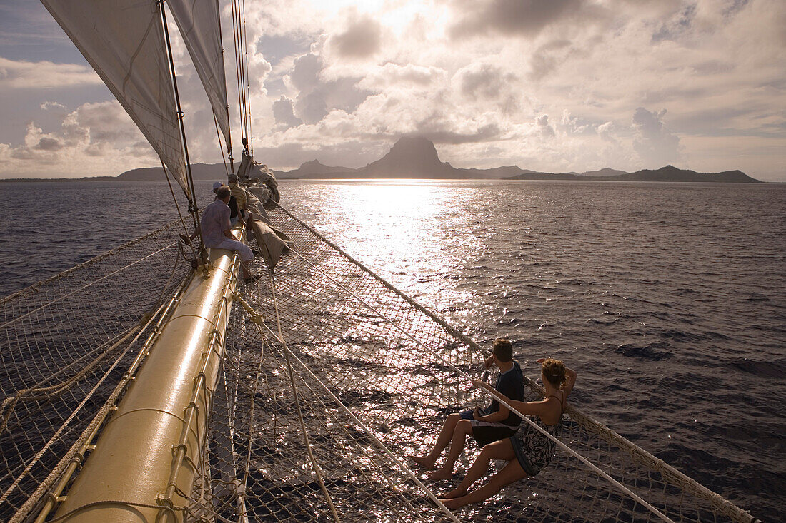 People relaxing on bowsprit and in net of sailing Cruiseship Star Flyer (Star Clippers Cruises), Bora Bora, Society Islands, French Polynesia