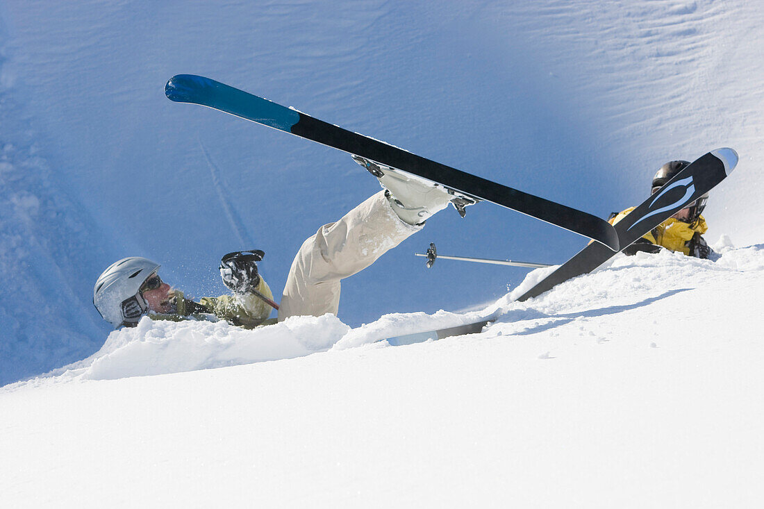 Two female skiers lying in the snow after a fall, Disentis, Grisons, Switzerland