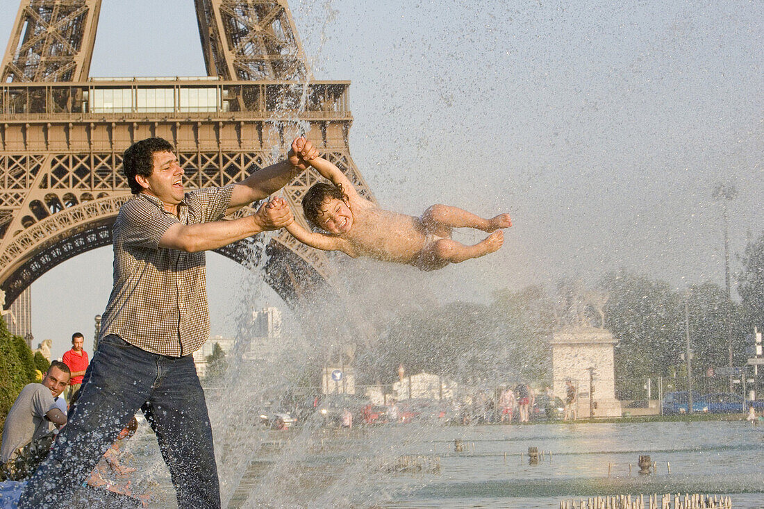 Father and son playing in the water of the fountain in front of the Eiffel Tower, Paris, France, Europe