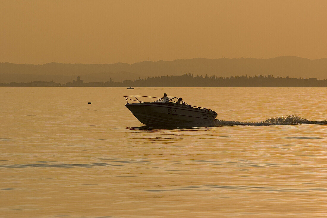 Kleines Motorboot auf dem Gardasee bei Sonnenuntergang, Italien, Europa