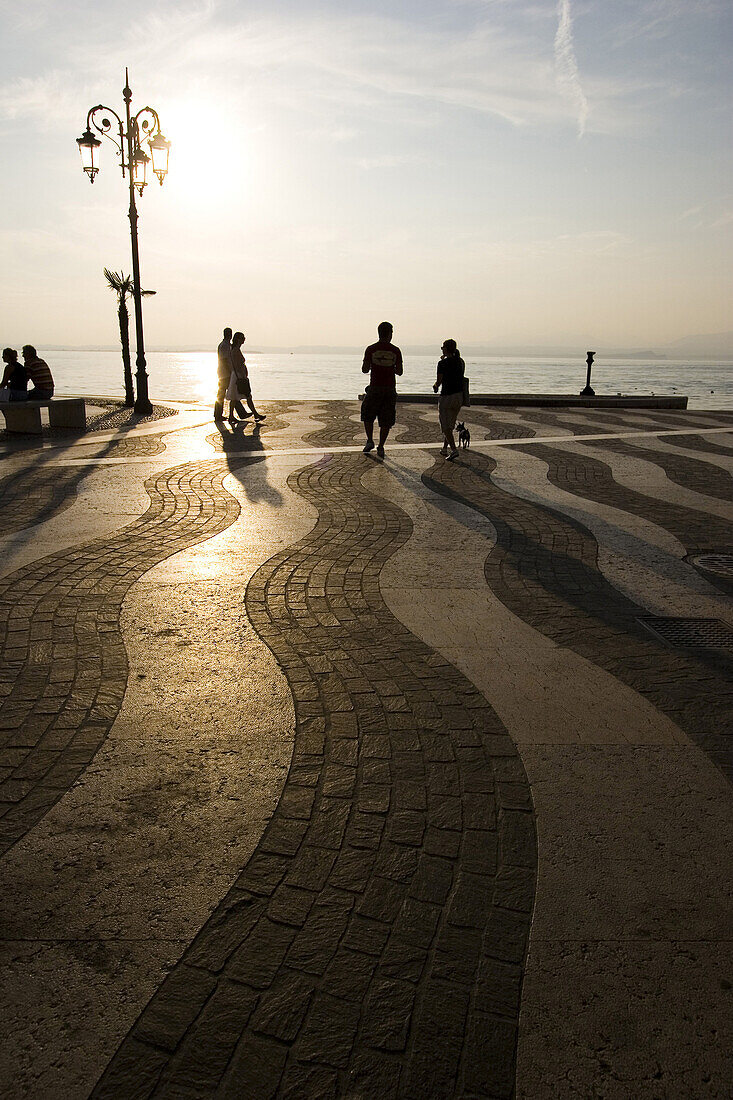 Menschen auf der Strandpromenade bei Sonnenuntergang, Lazise, Gardasee, Italien, Europa