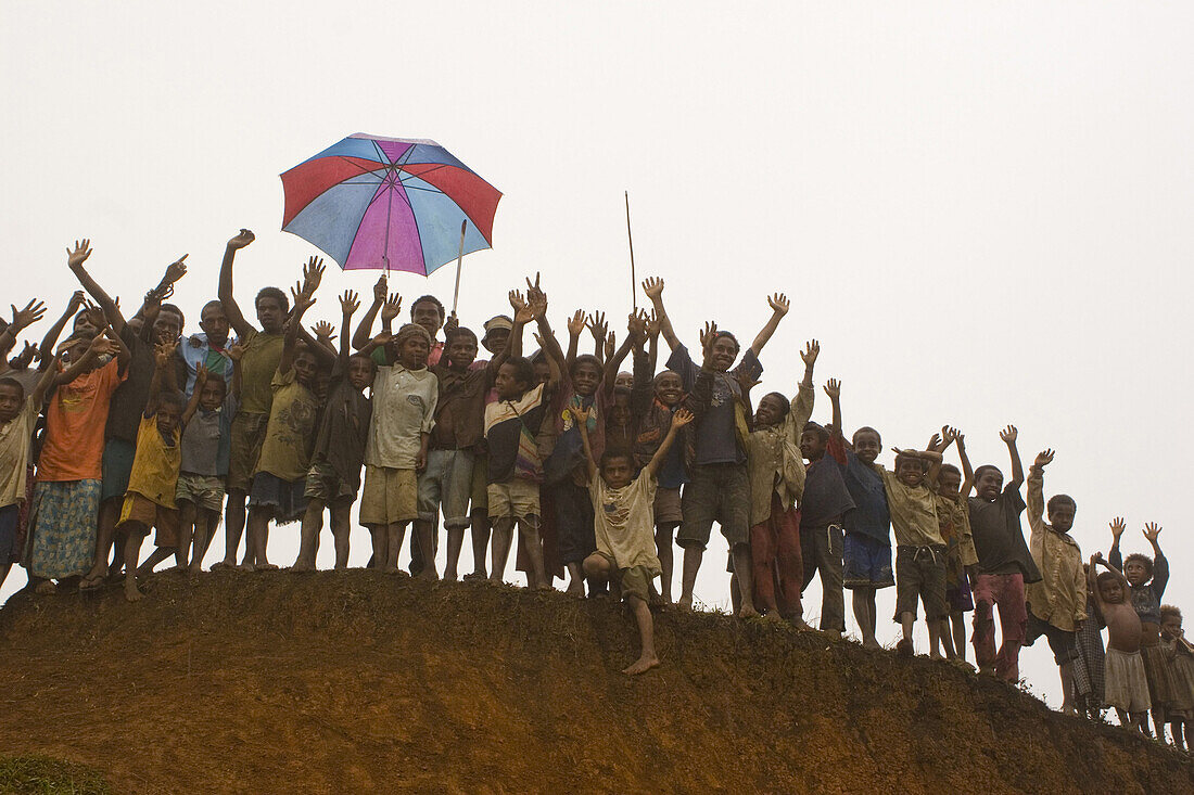 Eine Gruppe jubelnder Kinder mit Regenschirm, Langila, Papua Neuguinea, Ozeanien