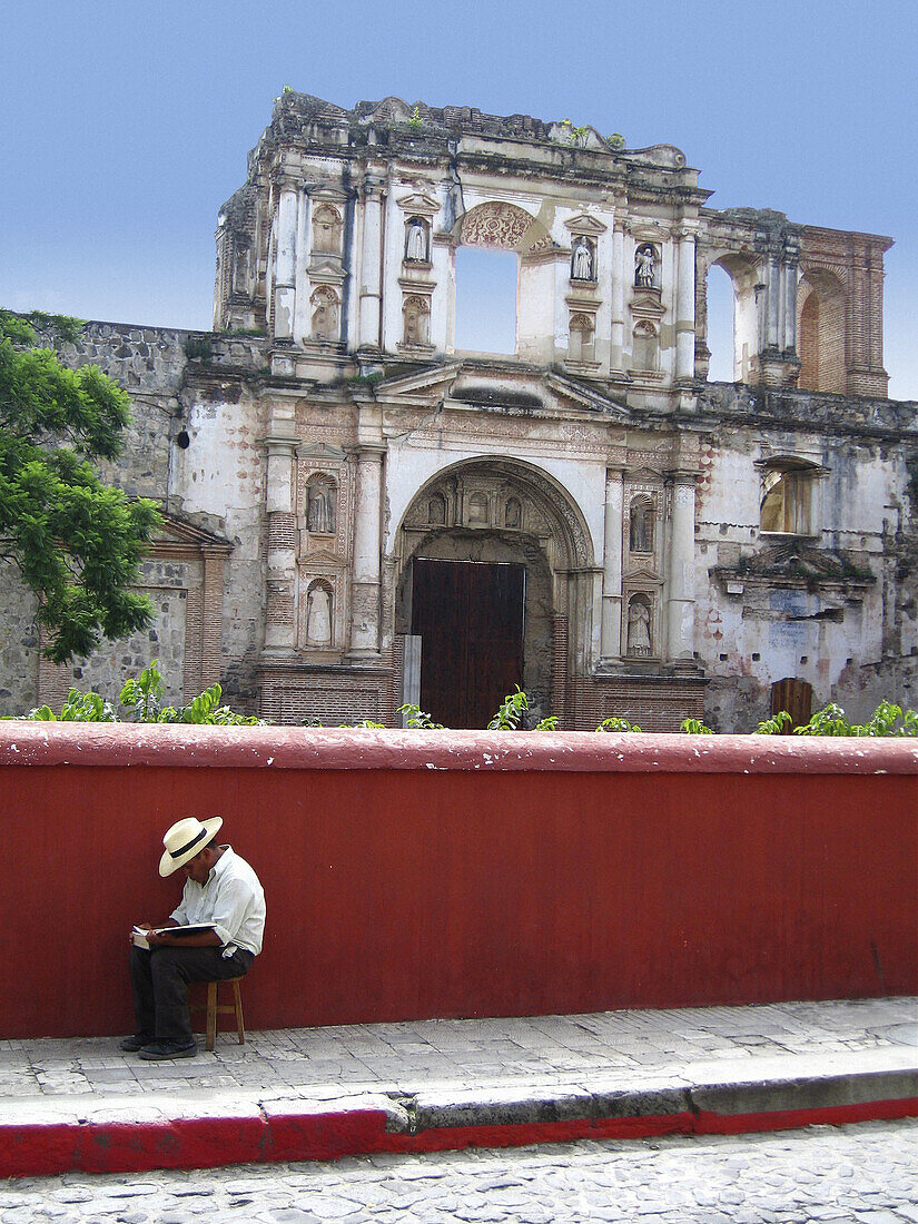 Man reading a book in the street. Antigua Guatemala. Departament of Sacatepéquez. Guatemala. Central America