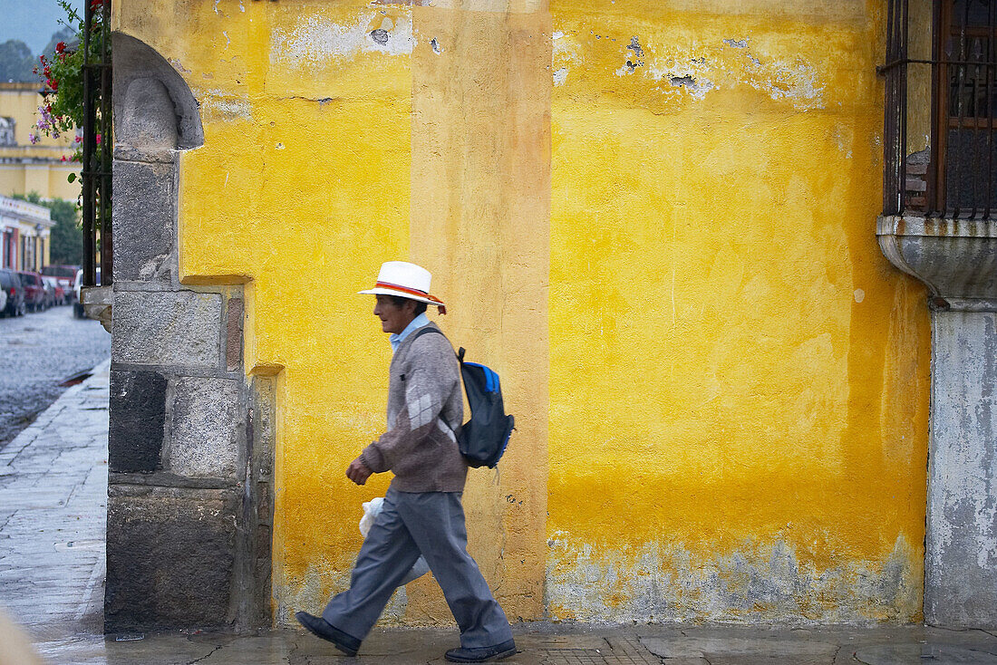 Picture from a man walking in front a painted wall. Antigua Guatemala. Sacatepéquez Region. Guatemala