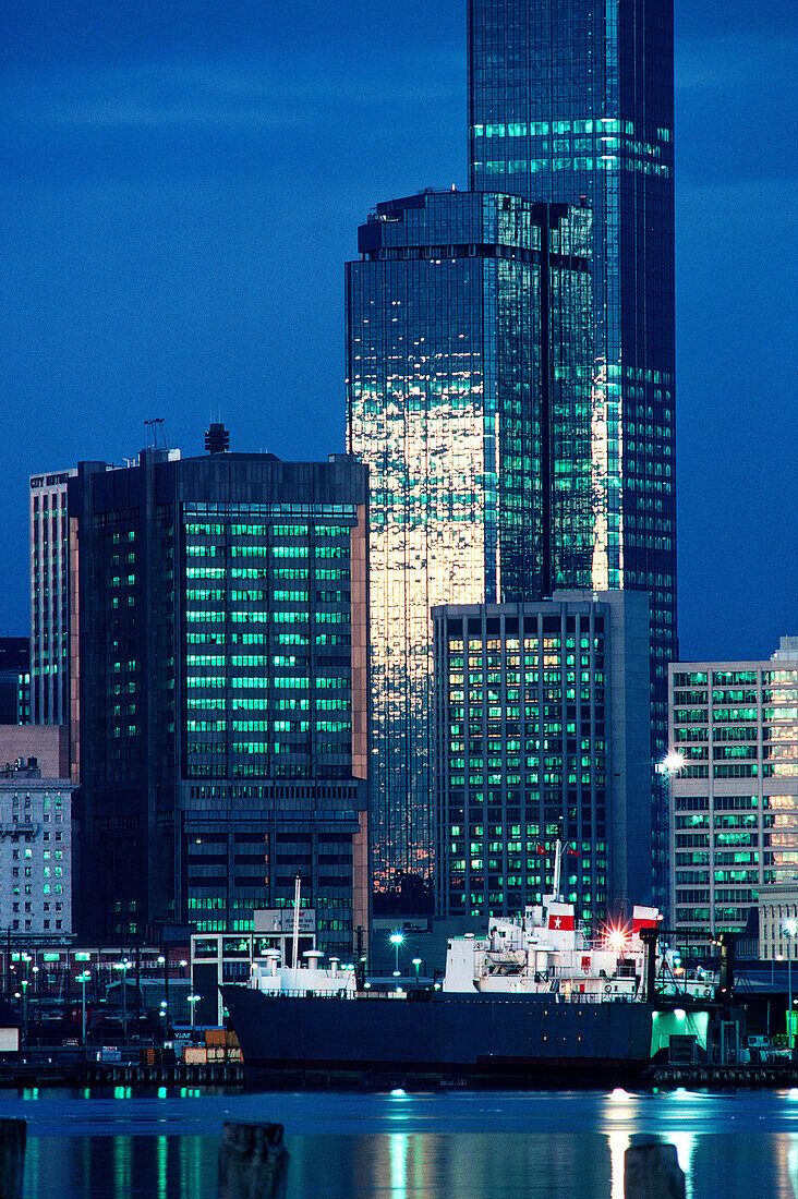 Roll-on roll-off (RORO) cargo ship in dock against city skyline buildings at dusk. Melbourne. Australia