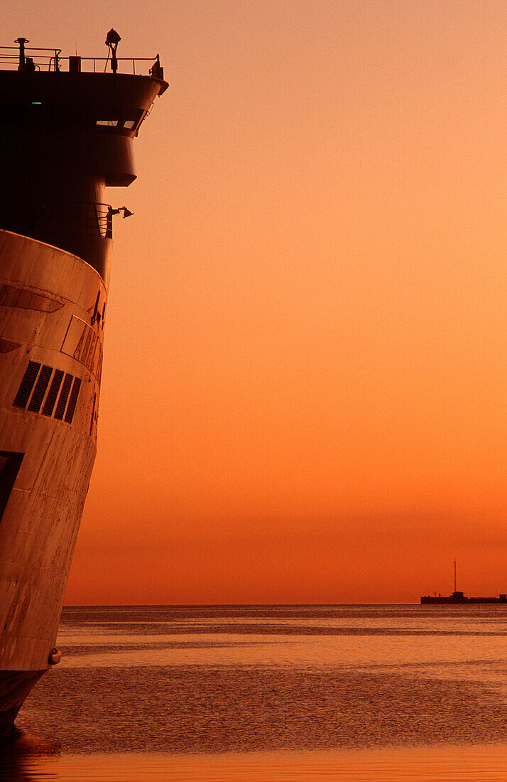 Passenger ship in dock at sunset.