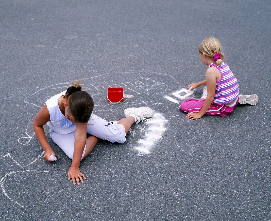 Young girls drawing on pavement with chalk. Anacortes, Skagit County. Washington, USA
