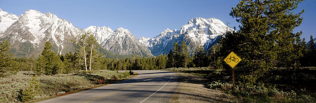 Bicycle caution sign along highway, Mt. Moran and Teton mountain range, Grand Teton National Park. Teton County, Wyoming, USA