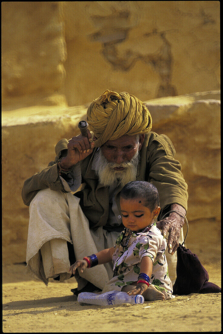 Old man taking care of a child in the surroundings of Thar Desert. Rajasthan. India