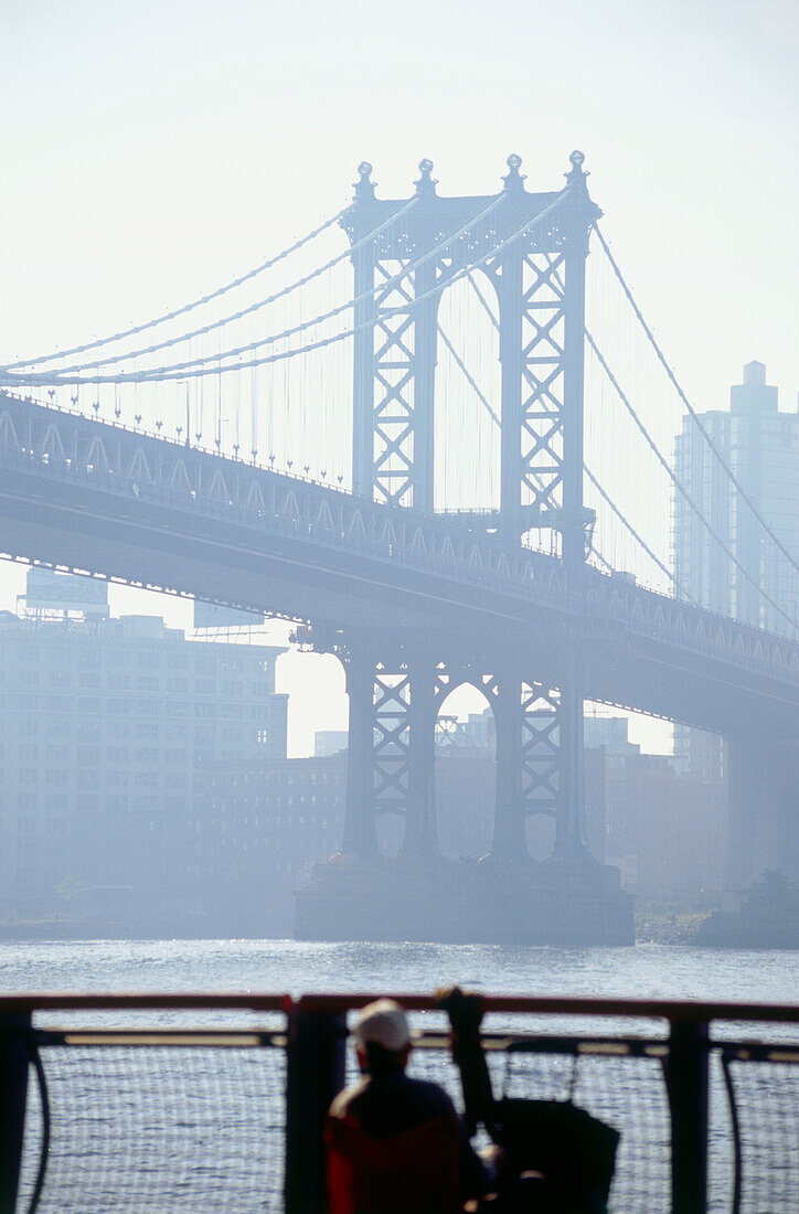 Fisherman on bank of East River with view to Manhattan Bridge, New York, USA, America