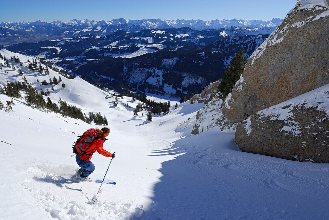 Junge Frau bei Pulverschneeabfahrt vom Gündleskopf mit Blick auf den Allgäuer Hauptkamm, Nagelfluhkette, Allgäuer Alpen, Allgäu, Schwaben, Bayern, Deutschland