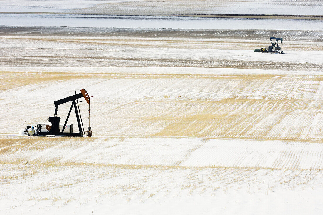 Oil well pump jack in snowy prairie. Alberta, Canada