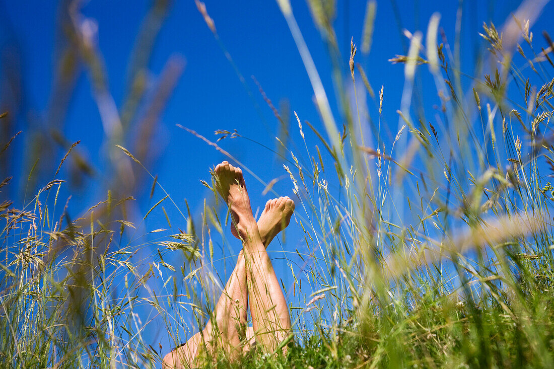 Barefoot woman lying on meadow, Upper Bavaria, Germany
