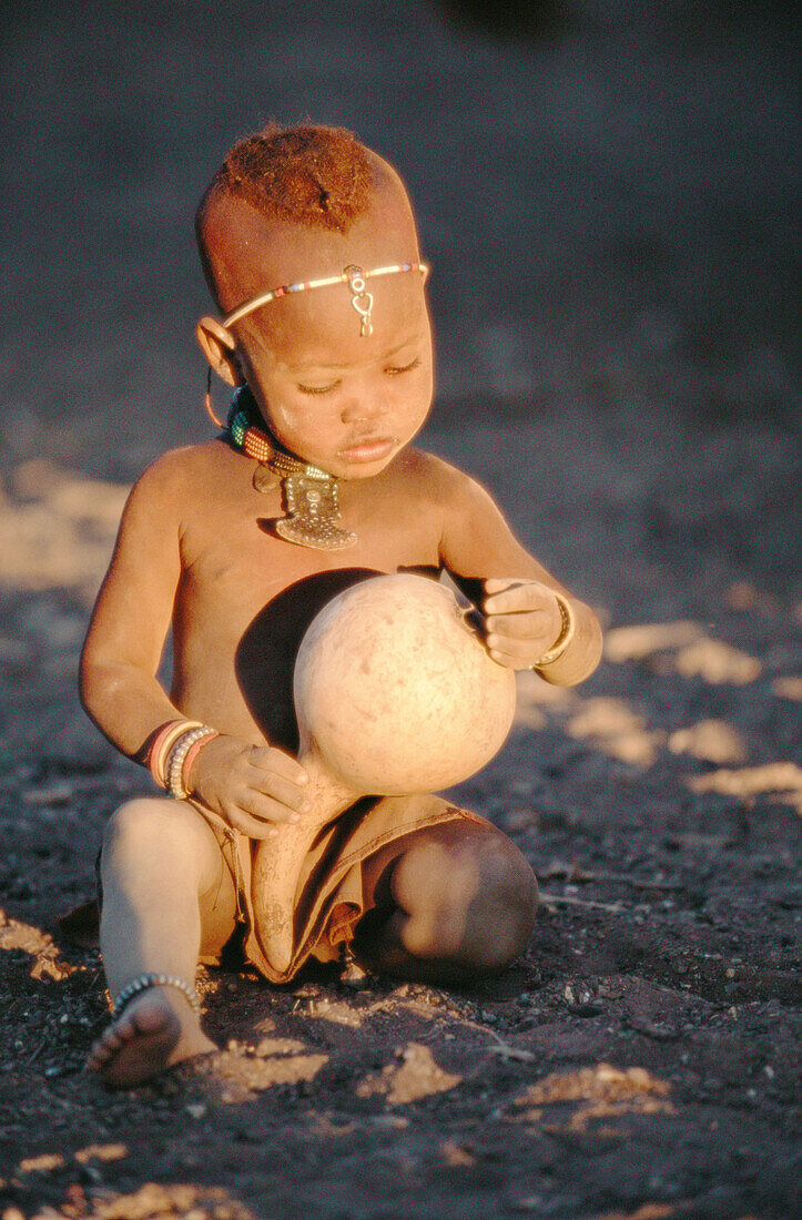 Himba child with pumpkin. Kaokoveld. Namibia.