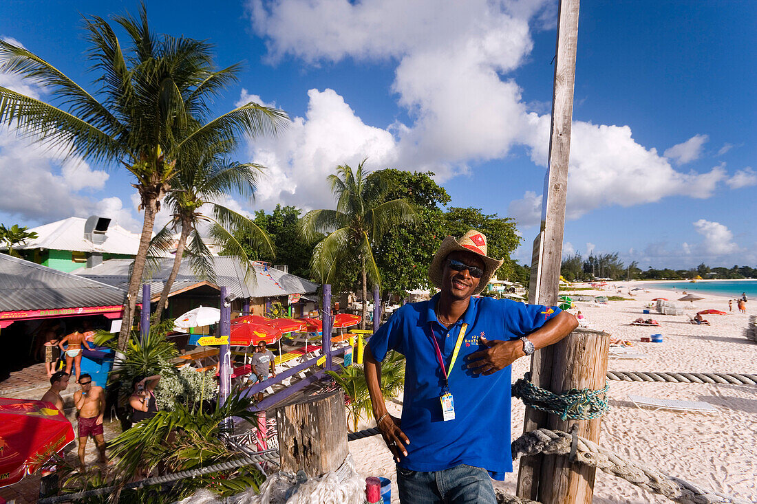 Man smiling at camera, the Boatyard beach bar in background, Bridgetown, Barbados, Caribbean