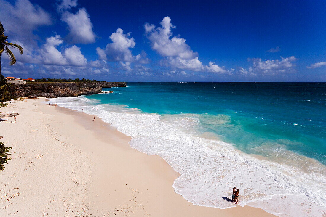 Couple standing in spray of Atlantic Ocean at Bottom Bay, St. Philip, Barbados, Caribbean